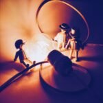 selective focus photography of three men figurines near lighted light bulb